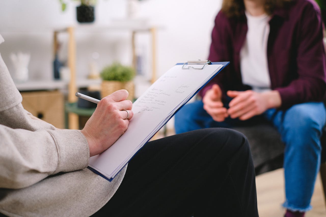 The Art of Drawing Readers In: Your attractive post title goes here Close-up of a therapist writing notes on a clipboard while conversing with a patient.
